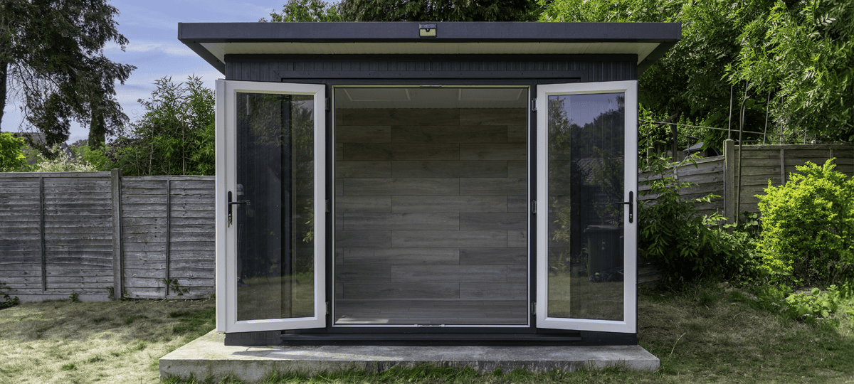 A small black and white garden shed with a door open.